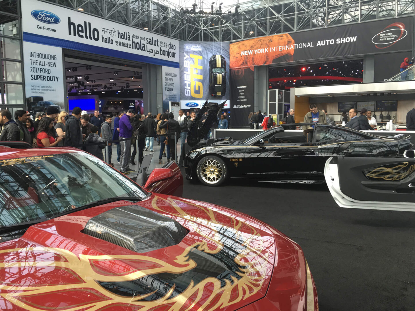 A group of people standing around cars on display.